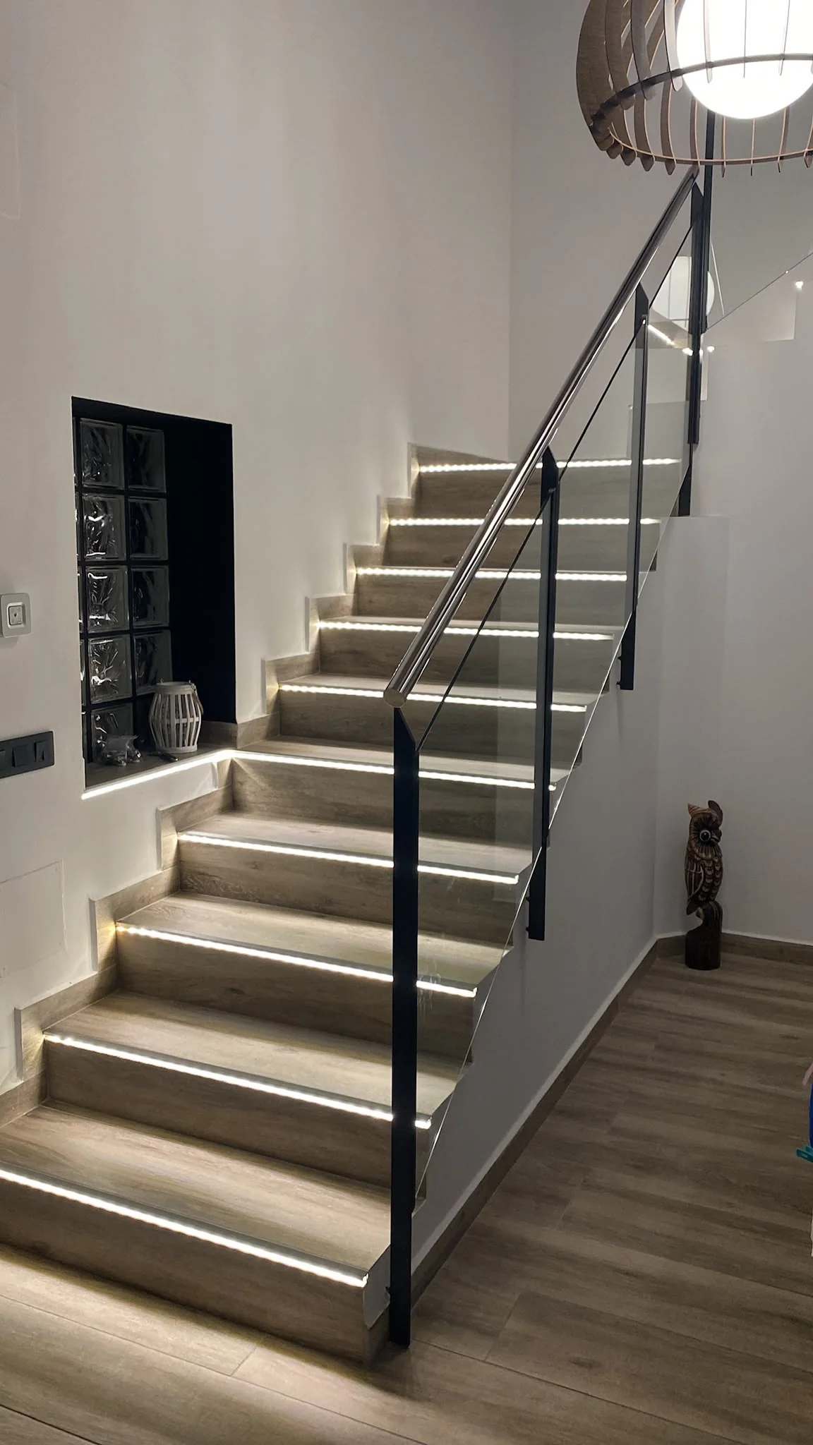 Escalera con iluminación integrada y barandilla de vidrio en un trabajo de Grupo Diper