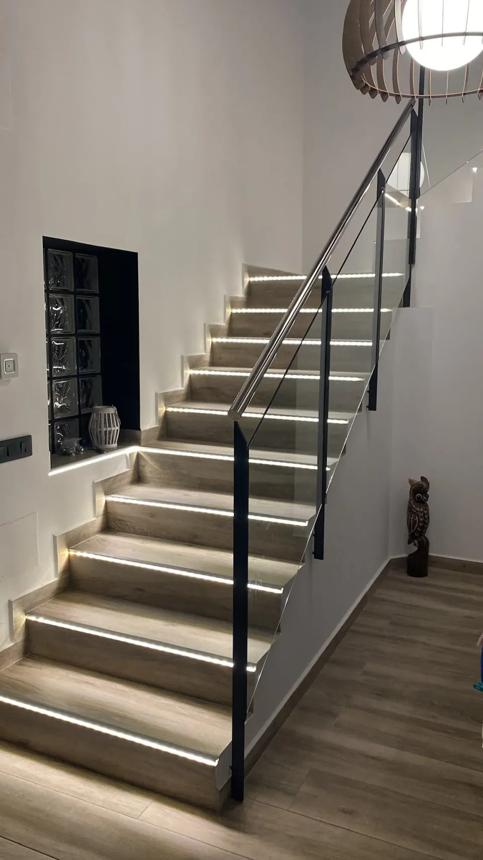 Escalera con iluminación integrada y barandilla de vidrio en un trabajo de Grupo Diper